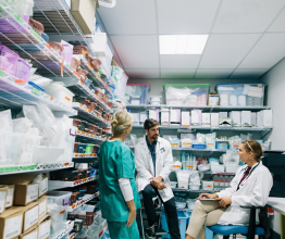 Two doctors and a nurse having a conversation in a hospital pharmacy.