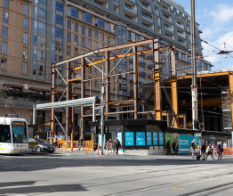 A construction site for the Metro Tunnel Project on Swanston Street. There is a tram next to the construction site.
