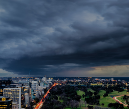 Dark storm clouds rolling in over high-rise buildings and parklands.