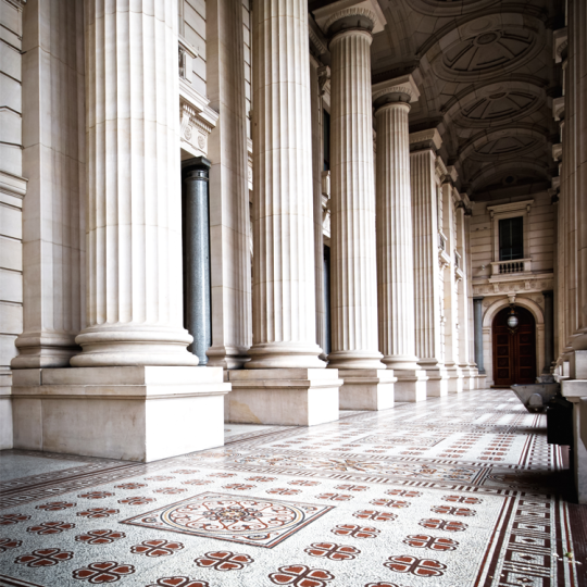 External columns and a tiled floor leading to an entrance of Parliament House in Victoria.