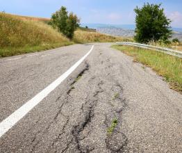 Image shows damaged road - cracked roadway. Photo courtesy of Tupungato/Shutterstock.com