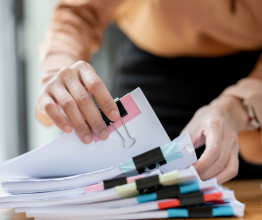 Close-up of a person's hands as they sort through a pile of documents.